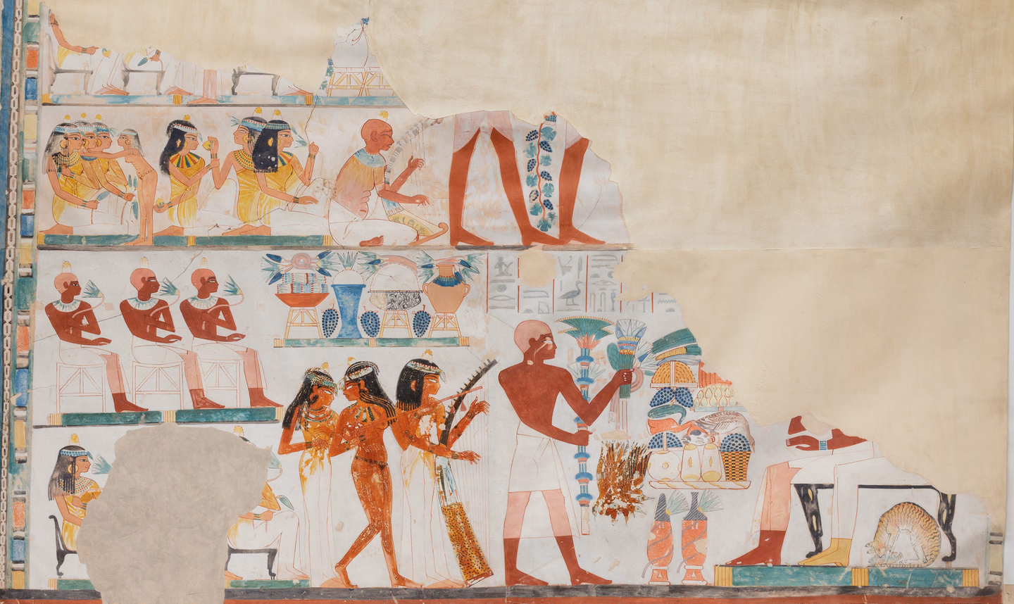 A painted copy of an ancient Egyptian wall scene in rows: seated women passing flowers, three musicians with a harp and a lute, a standing man holding tall bouquets, and tables piled with food and jars, with a large blank area where the original wall is missing