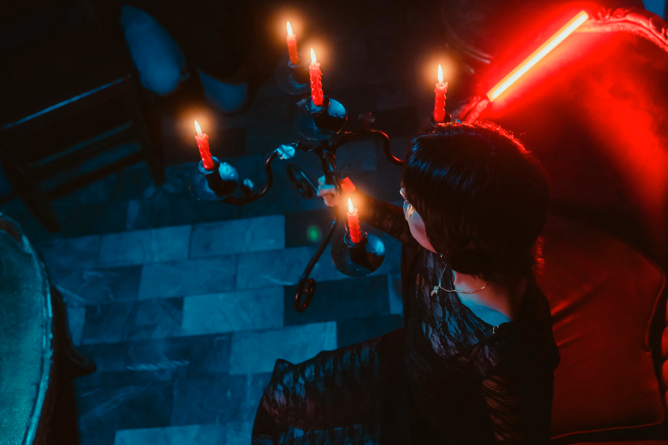 Dimly lit Victorian parlor with candelabras, velvet curtains, and a seance table set for six
